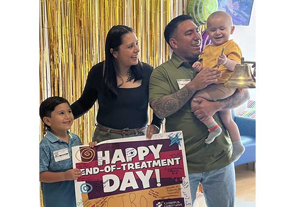 Ciro, his parents, and his brother holding a sign that says "Happy end-of-treatment day" at CHRISTUS Children's