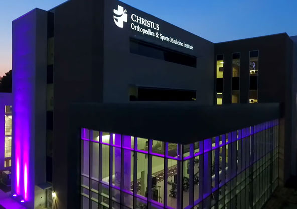 CHRISTUS Health's Orthopedic Sports Medicine Institute in Tyler pictured at dusk with purple lights.