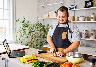 Man cooking healthy good while watching a video on computer