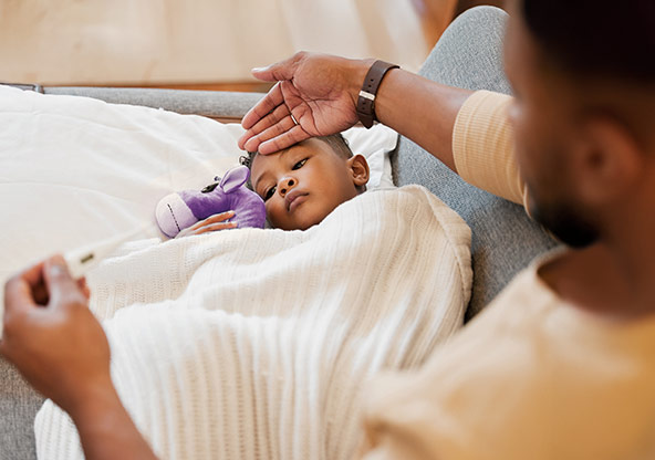 A dad feels his son's temperature 